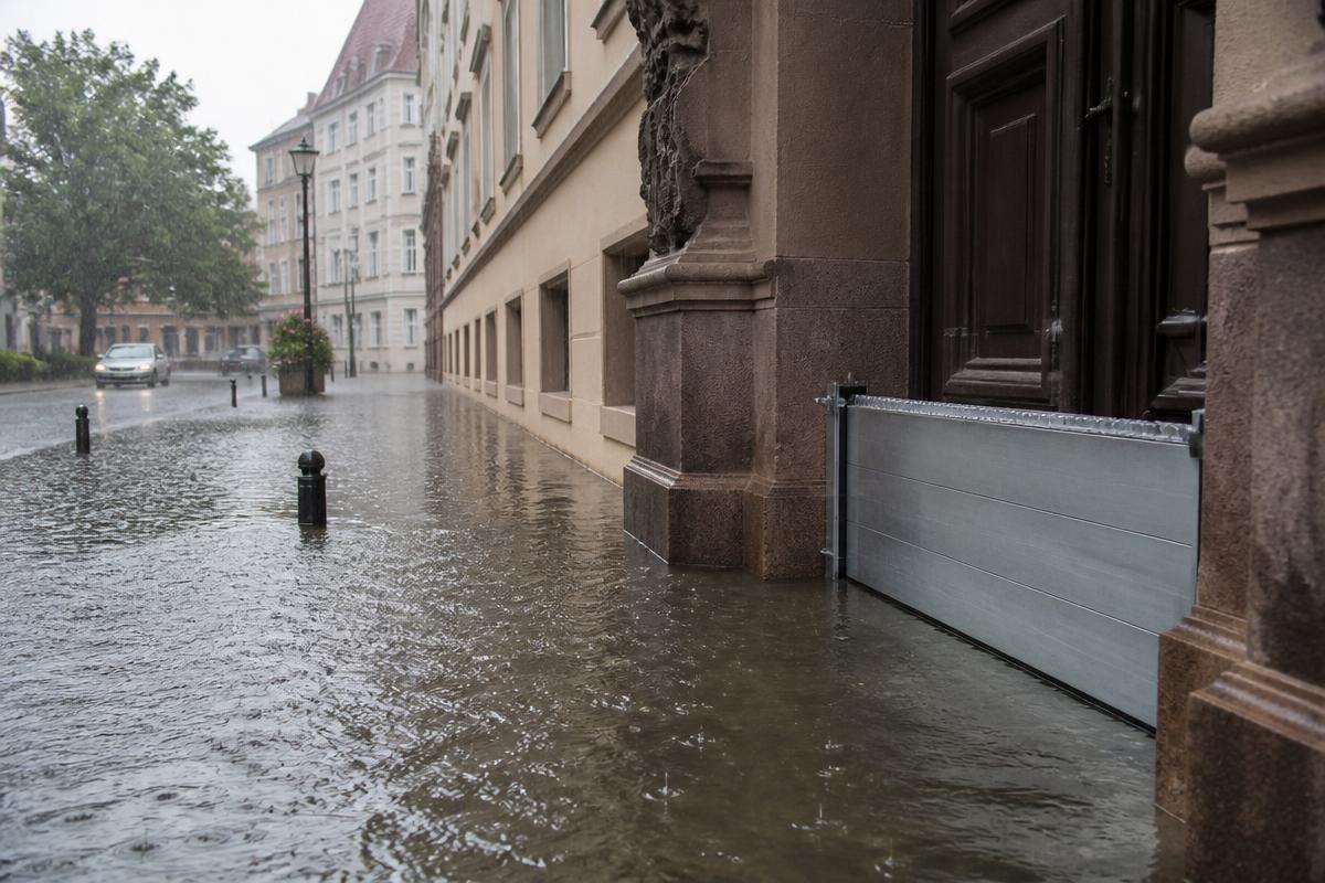 Überflutete Straße mit Wasserbarriere vor dem Eingang eines öffentlichen Gebäudes
